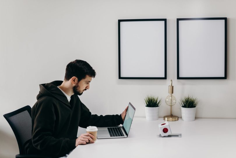 man in black coat sitting at the table man men laptop productivity