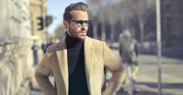 selective focus photo of man wearing black turtleneck top with jacket on road