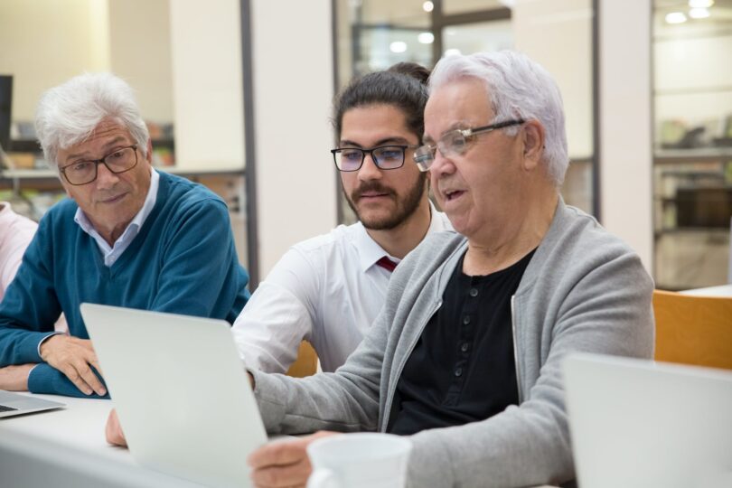 a man teaching elderly people about modern technology