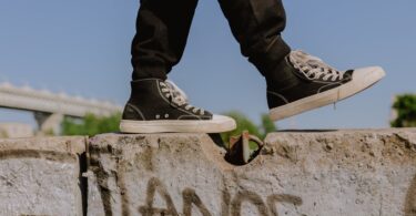 a person wearing black sneakers walking on concrete wall