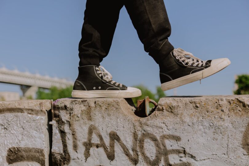 a person wearing black sneakers walking on concrete wall