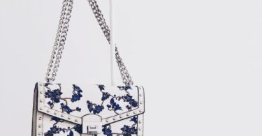 white and blue floral flap sling bag hanging on white steel rack