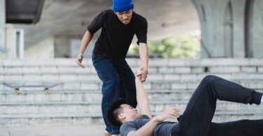 young asian man helping friend on pavement