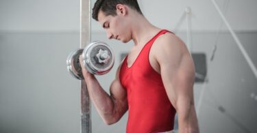 photo of male gymnast doing dumbbell bicep curls