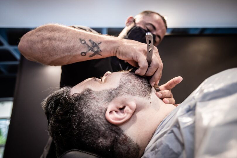 a barber shaving the beard of a client