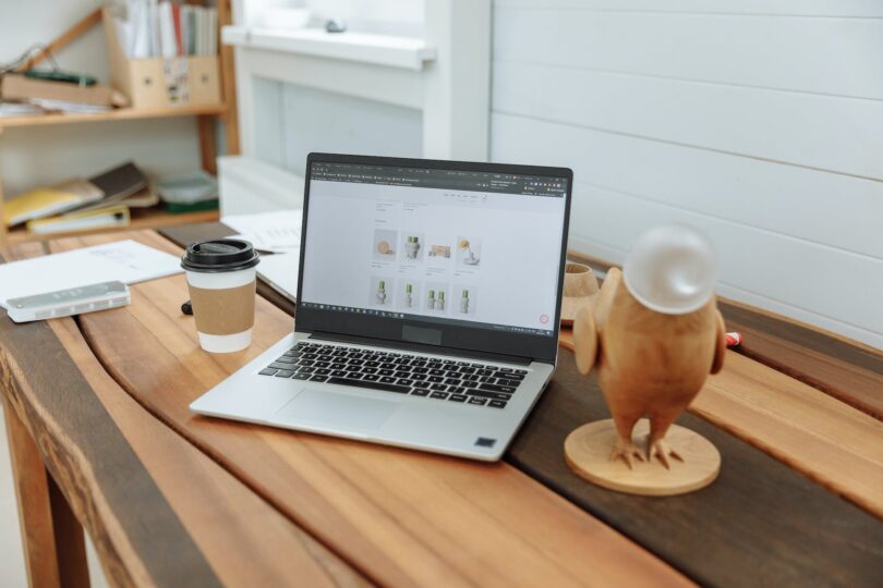 laptop on a wooden table with the design business website on the screen