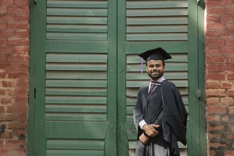 a man with a square academic cap smiling