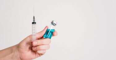 person holding syringe and vaccine bottle