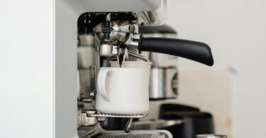 coffee machine pouring cappuccino into cup in modern cafe