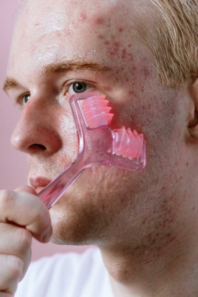 man holding pink plastic hair comb